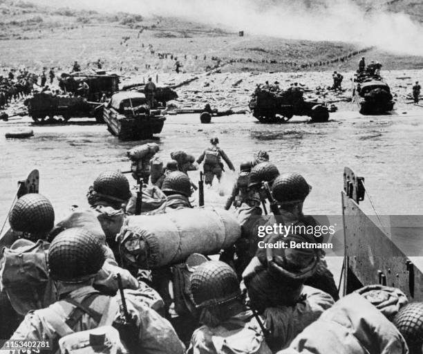 Battle equipped American troops splash ashore to the Normandy coast of France in initial phase of the beachhead landings. An amphibious "duck" and...
