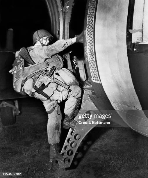 This American paratrooper, going aboard a transport plane at a British airbase before takeoff for the invasion of Europe, seems remarkably happy for...