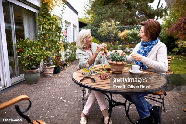 two happy senior women crafting at garden table - coffee on patio stock pictures, royalty-free photos & images