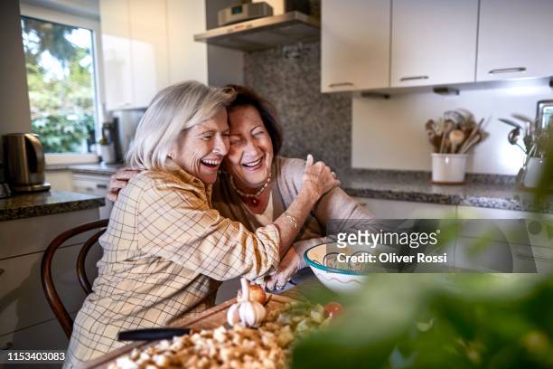two happy senior women preparing food together in kitchen - woman laugh cook stock pictures, royalty-free photos & images