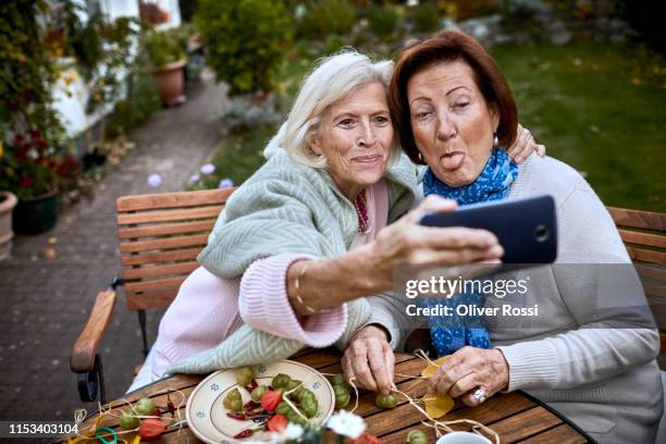 happy senior friends taking a selfie at garden table - memorial garden stock pictures, royalty-free photos & images