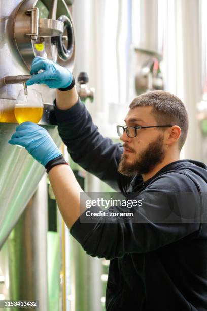brewer prueba cerveza del tanque de fermentación - fábrica de cerveza artesanal fotografías e imágenes de stock