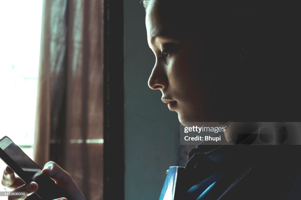 Girl holding book and texting on mobile phone