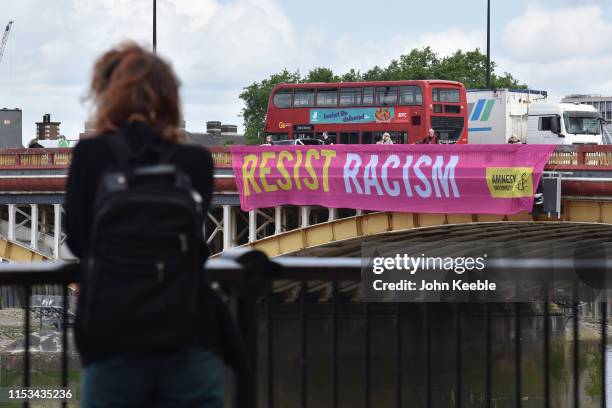 Woman looks at a Resist Racism banner as Amnesty International install 'Resist Trump' banners on Vauxhall Bridge following the arrival of US...