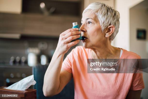 frau mit asthma-inhalator - asthmainhalator stock-fotos und bilder