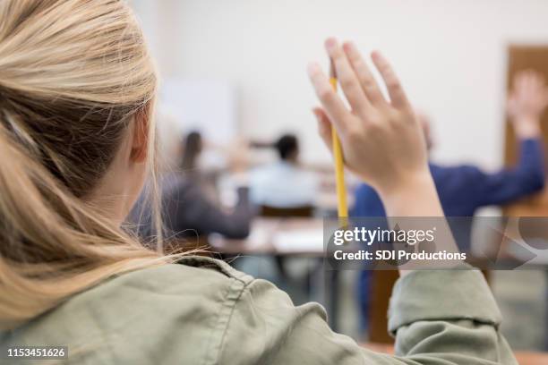 onherkenbaar kaukasische tiener verhoogt de hand in de klas - rear view girl stockfoto's en -beelden