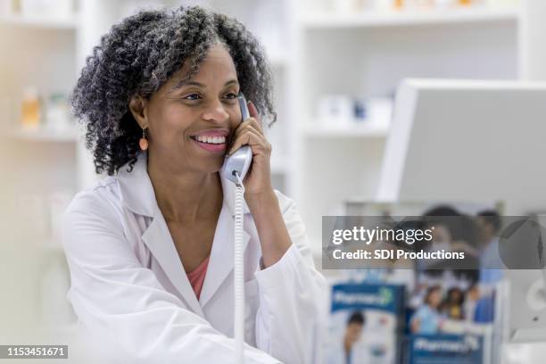 pharmacist consults computer records for patient - woman pharmacist stock pictures, royalty-free photos & images