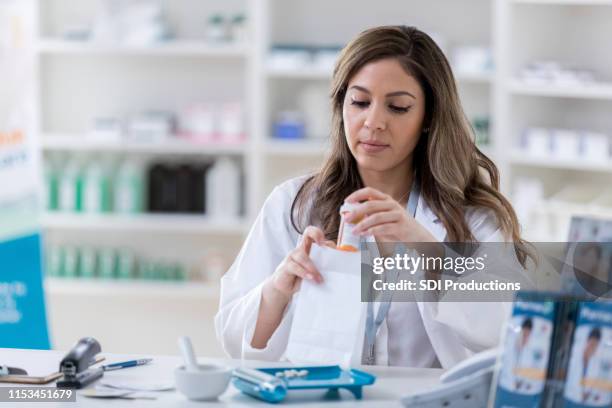 after compounding a medication, a pharmacist packages the bottle - prescription medicine stock pictures, royalty-free photos & images