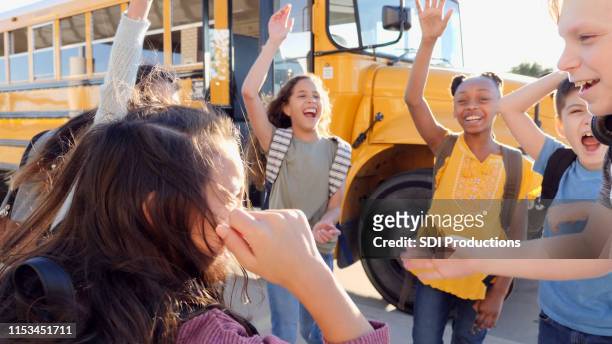 circle of playful children cheer loudly at bus stop - last day of school stock pictures, royalty-free photos & images
