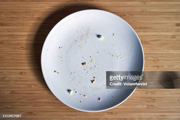 empty breakfast dish with bread crumbs on a bamboo wooden table - kitchen bench from above stock-fotos und bilder