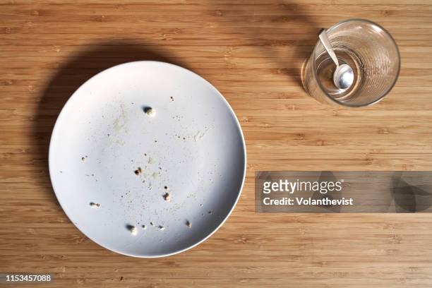 empty dish with bread crumbs and empty cup of coffee on a bamboo wooden table - kitchen bench from above stock-fotos und bilder