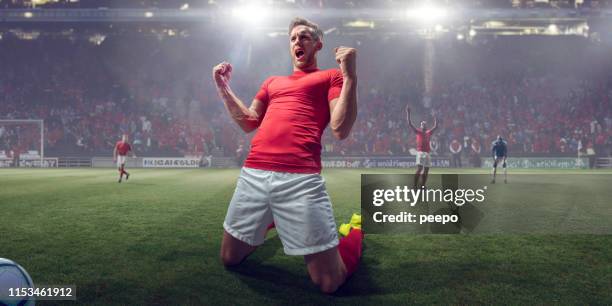professional soccer player celebrating victory on knees with fists clenched - football stadium low angle stock pictures, royalty-free photos & images
