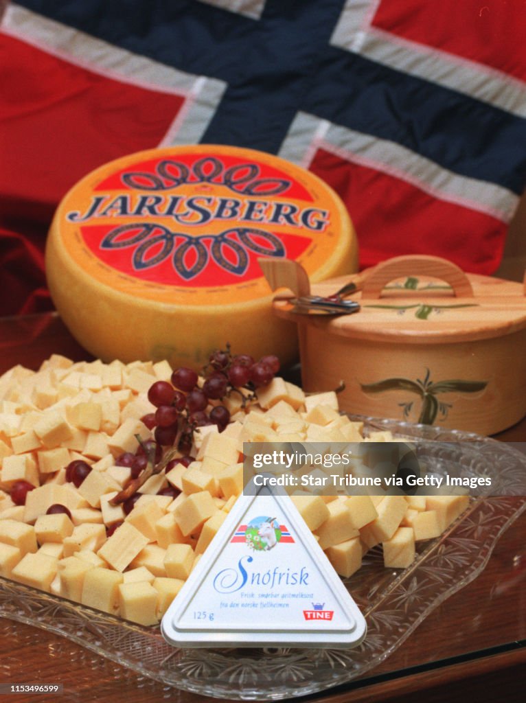 The new Norwegian cheese product, Snofrisk, introduced at the Sons of Norway, in anticipation of the visit of the king and queen of Norway. The triagular container, foreground, is Snofrisk. It is surrounded by chunks of Jarlsberg cheese as well as a compl