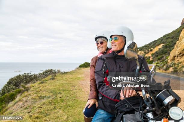 retired couple on a motorbike ride along a coastal road - old motorcycles imagens e fotografias de stock