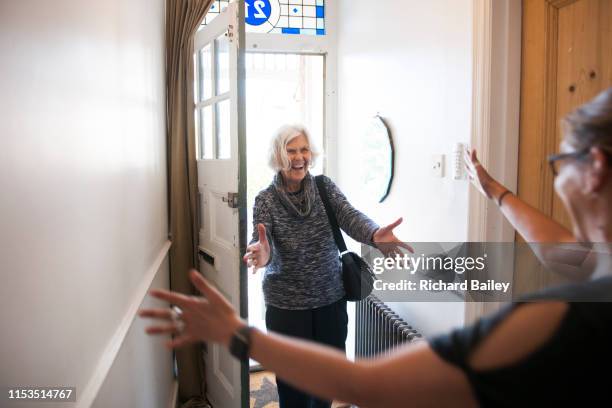 mature lady entering front door of house - zwaaien gebaren stockfoto's en -beelden