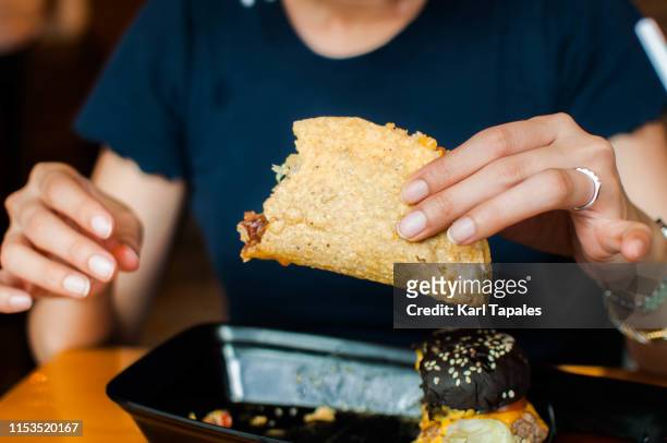a young woman is eating taco - パン　持つ　手　女性 ストックフォトと画像