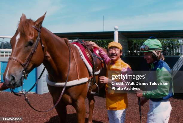 Pat Morita in jockey gear with horse, at racetrack, during the making of the ABC tv series 'Mr T and Tina'.