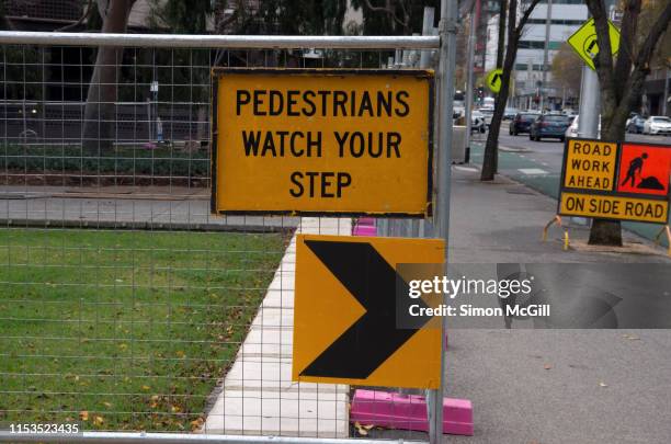 'pedestrians watch your step' warning sign on a construction barrier fence - trip hazard stock pictures, royalty-free photos & images