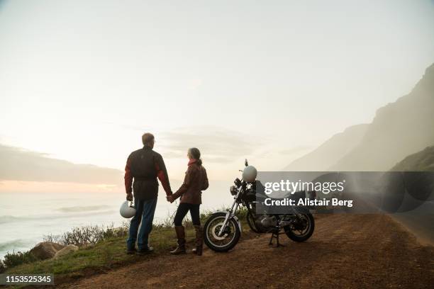 retired couple on a motorbike ride on a coastal road - moto fotografías e imágenes de stock