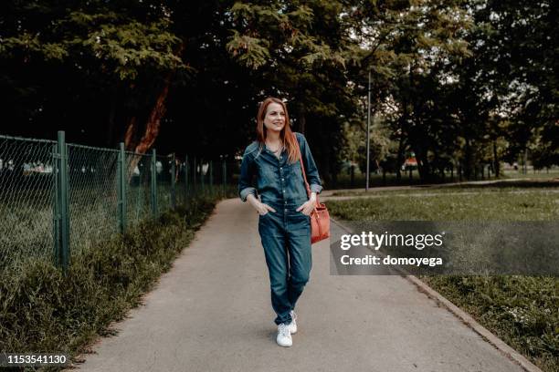 glückliche junge frau bei einem spaziergang im park - overalls stock-fotos und bilder