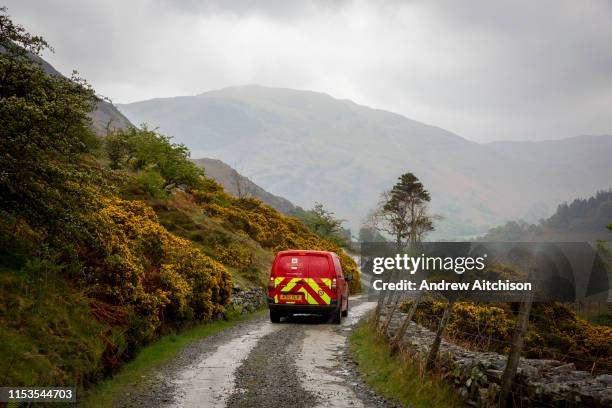 Red post office delivery van driving down Greenside Road, back down the valley to the village of Glenridding on the shore of Lake Ullswater, The Lake...
