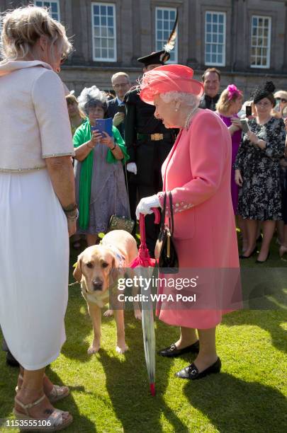 Queen Elizabeth II with Becky the guide dog at a garden party at The Palace Of Holyroodhouse on July 3, 2019 in Edinburgh, Scotland.