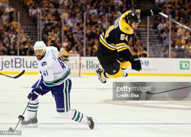 Adam McQuaid of the Boston Bruins flys through the air after being checked by Andrew Alberts of the Vancouver Canucks during Game Three of the 2011...