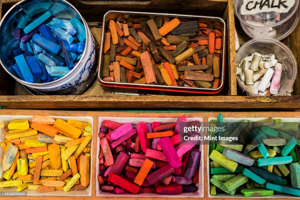 High angle close up of a wooden box with artist's crayons in a variety of vibrant colours.