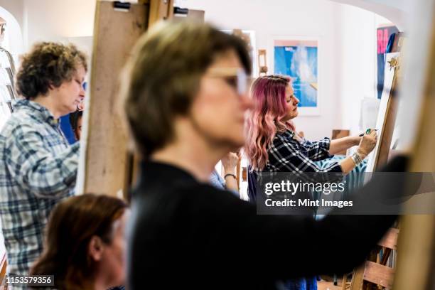 close up of a woman standing at an easel, drawing. - art class stock pictures, royalty-free photos & images