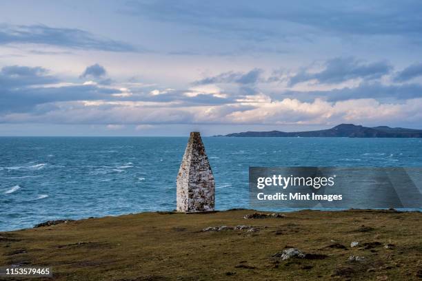 cardigan bay and stone cairn marking the entrance to porthgain harbour from the pembrokeshire coast trail, pembrokeshire national park, wales, uk. - wales winter stock pictures, royalty-free photos & images