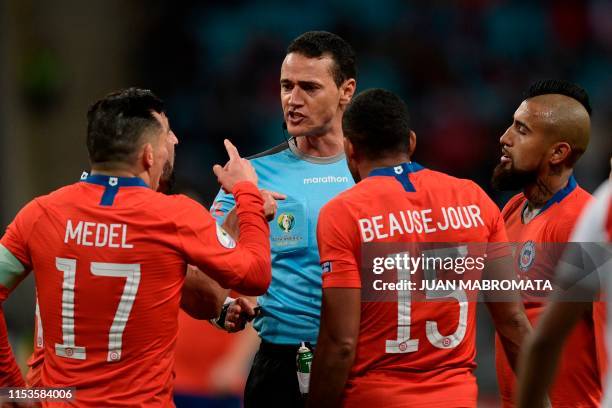 Colombian referee Wilmar Roldan listens to Chile's Gary Medel , Jean Beausejour and Arturo Vidal as he conducts the Copa America football tournament...