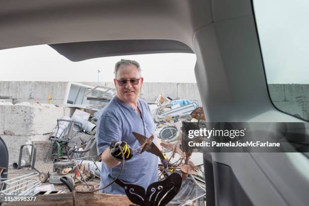 mature man unloading metal from car for recycling at depot - messy car interior stock pictures, royalty-free photos & images