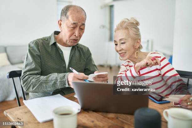 senior japanese couple managing home finances - saving up for a rainy day stock pictures, royalty-free photos & images