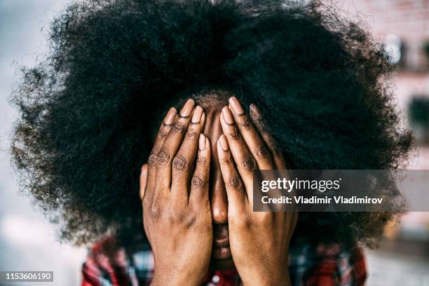 african woman sitting at home hands on face - hidden message stock pictures, royalty-free photos & images