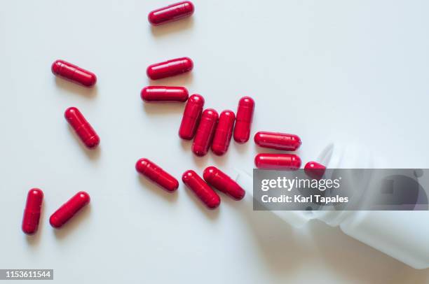 a close-up view of red medicine capsules on a white background - red pill stock pictures, royalty-free photos & images