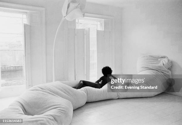 Naked woman lounging on an extra long beanbag sofa in a all-white furnished room, UK, 12th March 1970.