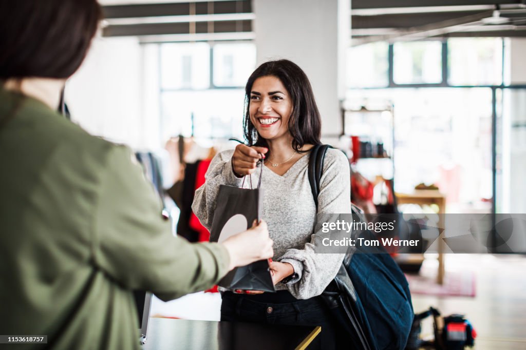 Store Clerk Handing Customer Purchased Items