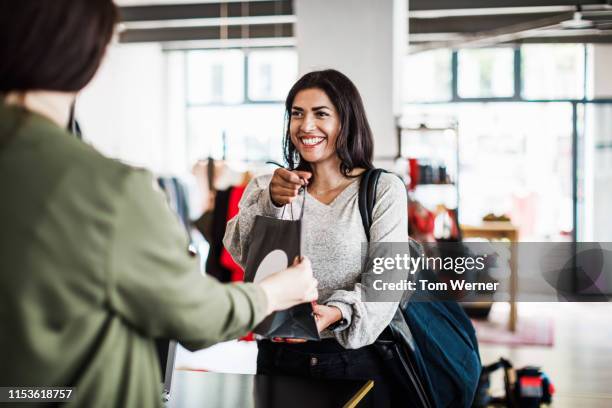 store clerk handing customer purchased items - 小売り ストックフォトと画像