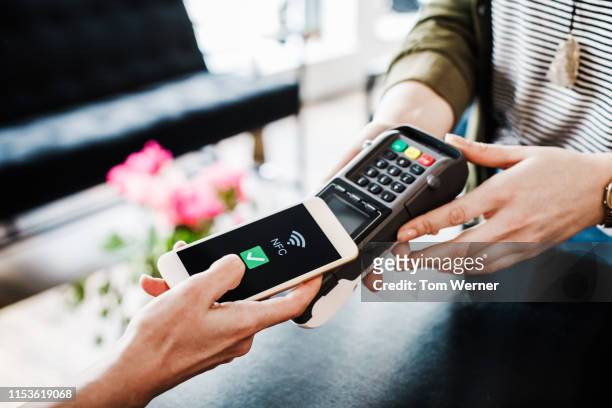 close up of woman using smartphone to pay for shopping - payer photos et images de collection