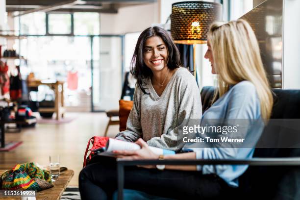 two women sitting down taking a break from shopping - female friendship stock pictures, royalty-free photos & images