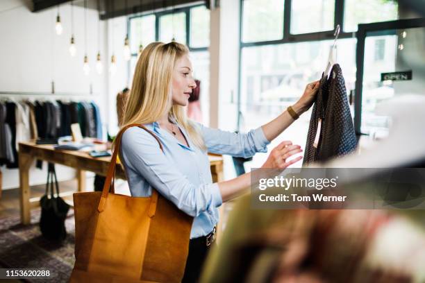 woman reading label on clothing while out shopping - merchandise stock-fotos und bilder