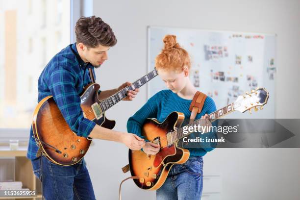 vrouwelijke student learning guitar van trainer - learn guitar stockfoto's en -beelden