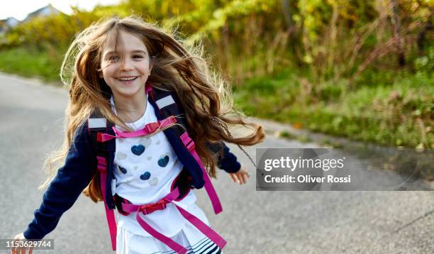 happy little girl with schoolbag on a country road - happy people running stockfoto's en -beelden