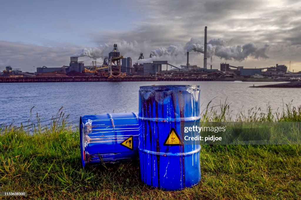 Chemical waste drums in front of heavy industry