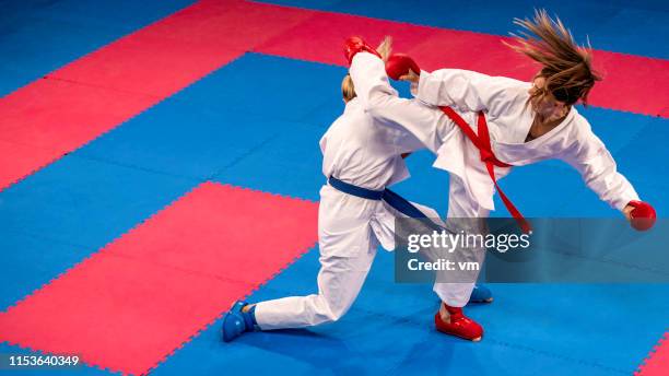 two female karate practitioners sparring on a tatami mat - taekwondo sparring stock pictures, royalty-free photos & images