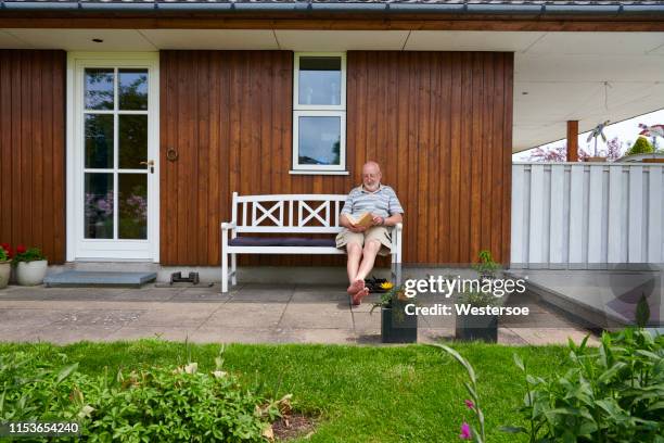 ruheständler, der auf einer bank außerhalb seines hauses ruht - house denmark stock-fotos und bilder