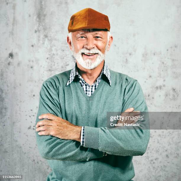 senior man in sweater and beret posing - bereit stock pictures, royalty-free photos & images