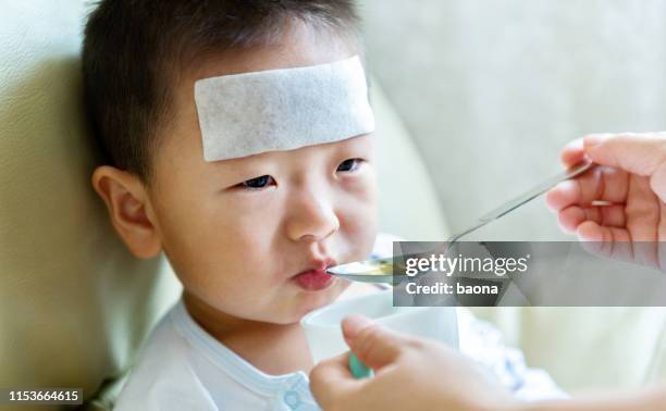 sick little boy taking medicine liquid syrup from his mother - hand over mouth stock pictures, royalty-free photos & images