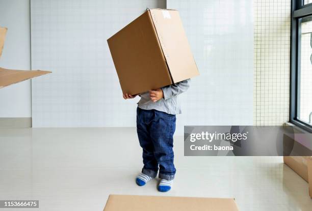 kleine jongen spelen in een doos op bewegende dag - boy jeans stockfoto's en -beelden