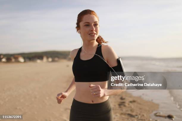 a young woman running on the beach - jogging photos et images de collection